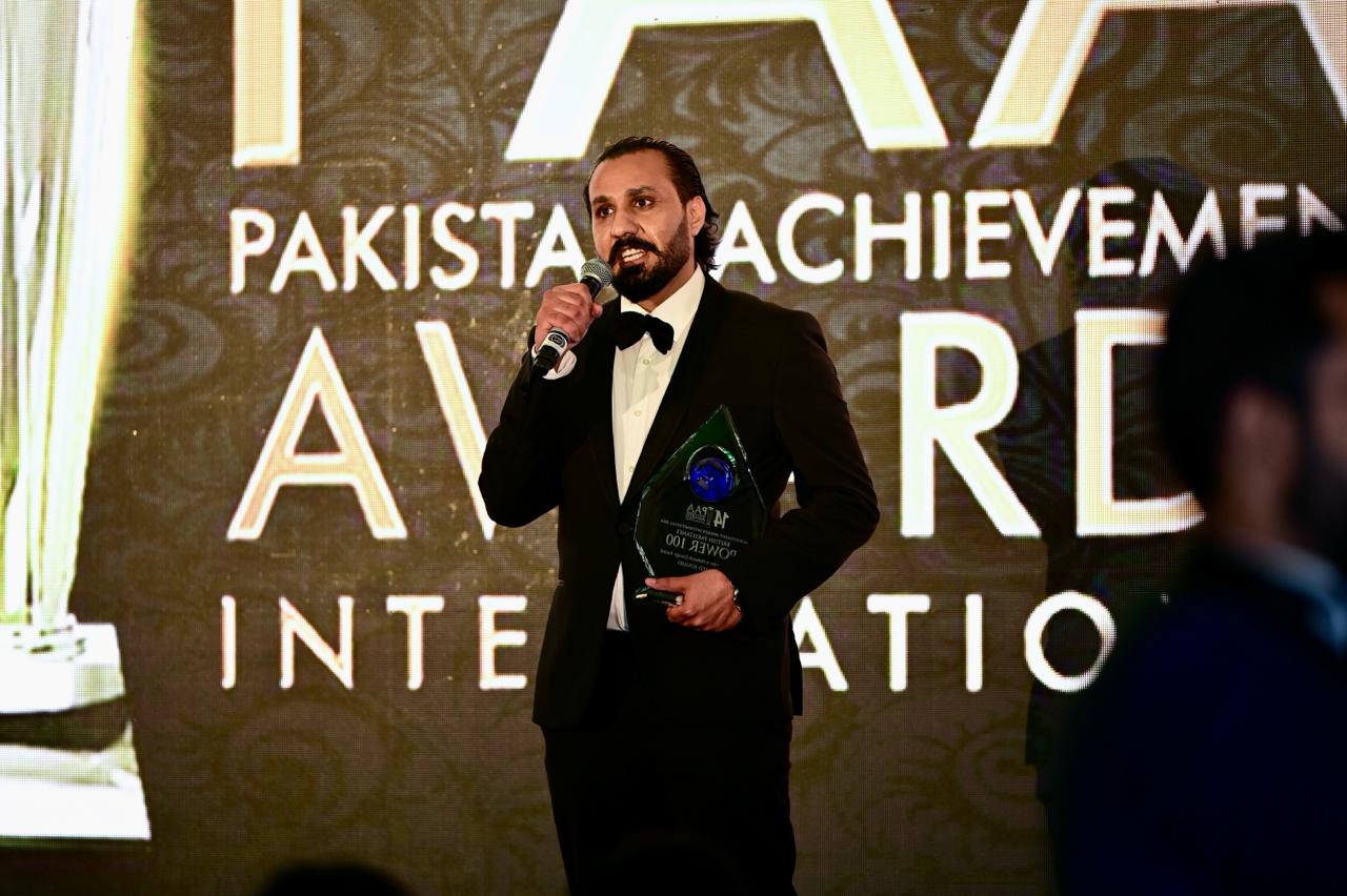 Ahmed Junaid speaking on stage at an awards event